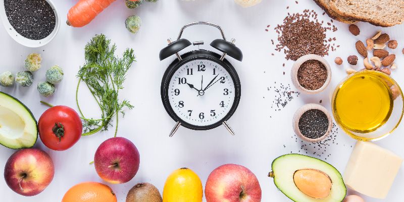 a watch in the middle surrounded by various healthy foods