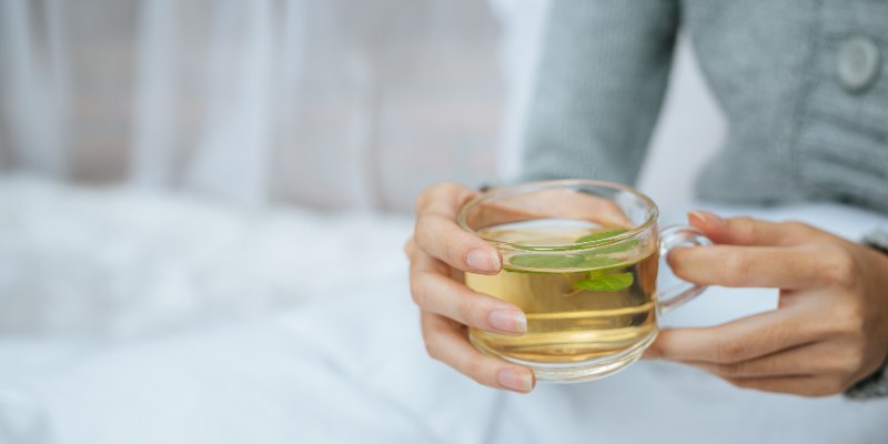 a woman holding a glass of green tea
