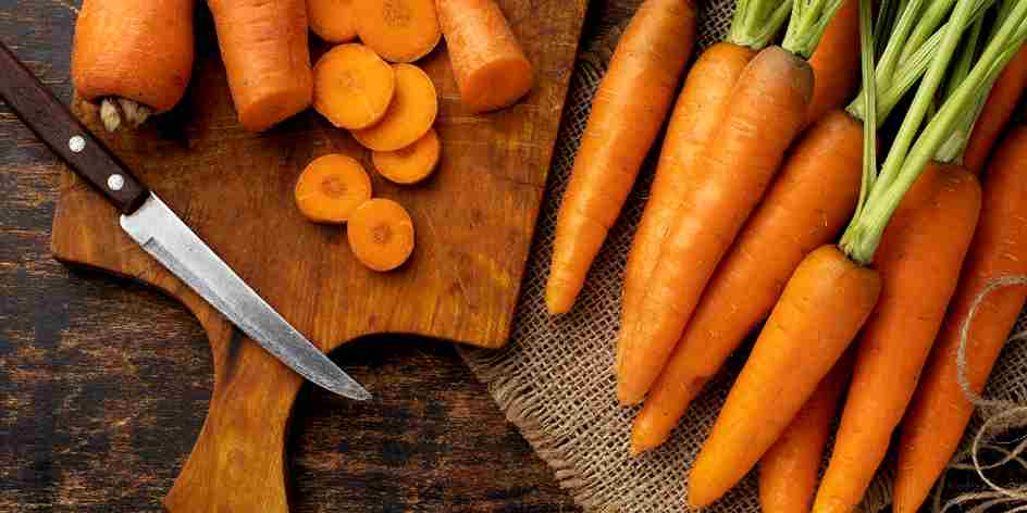 a lot of carrots with a knife placed in a chopping board